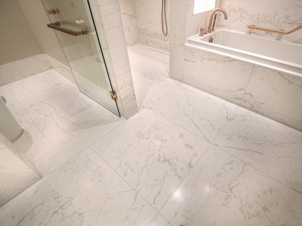 Panoramic photo of a glamorous bathroom with white marble Pirgon stone tiles with veins on the bath floor, shower wall surface and bathtub cladding