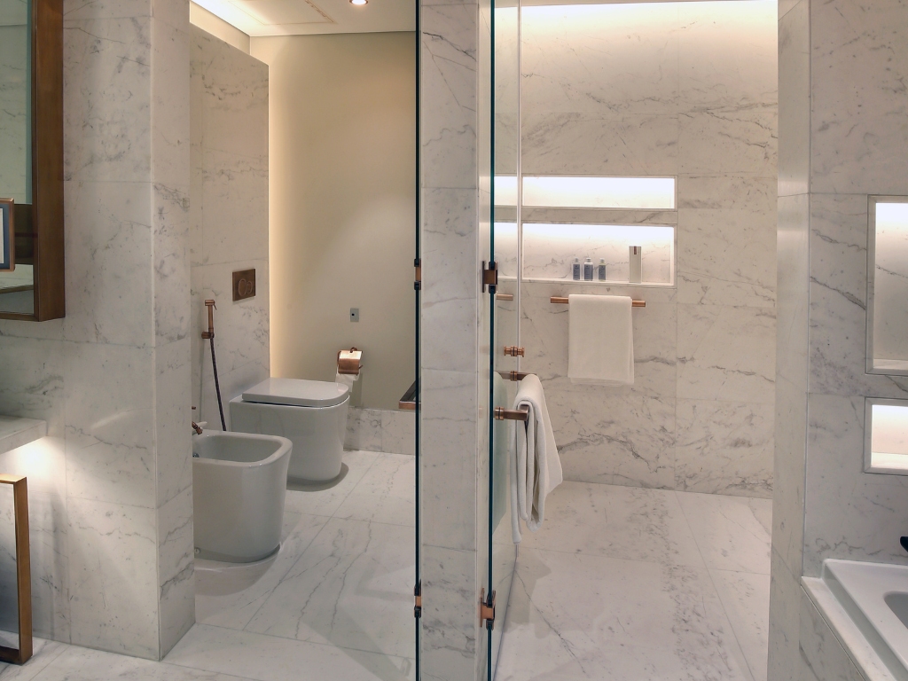Master bathroom with separate shower room and toilet room, with white marble tiles on bath wall surfaces and bath floor