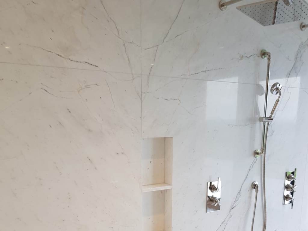 Close up image of a shower wall with white book-match marble slabs
