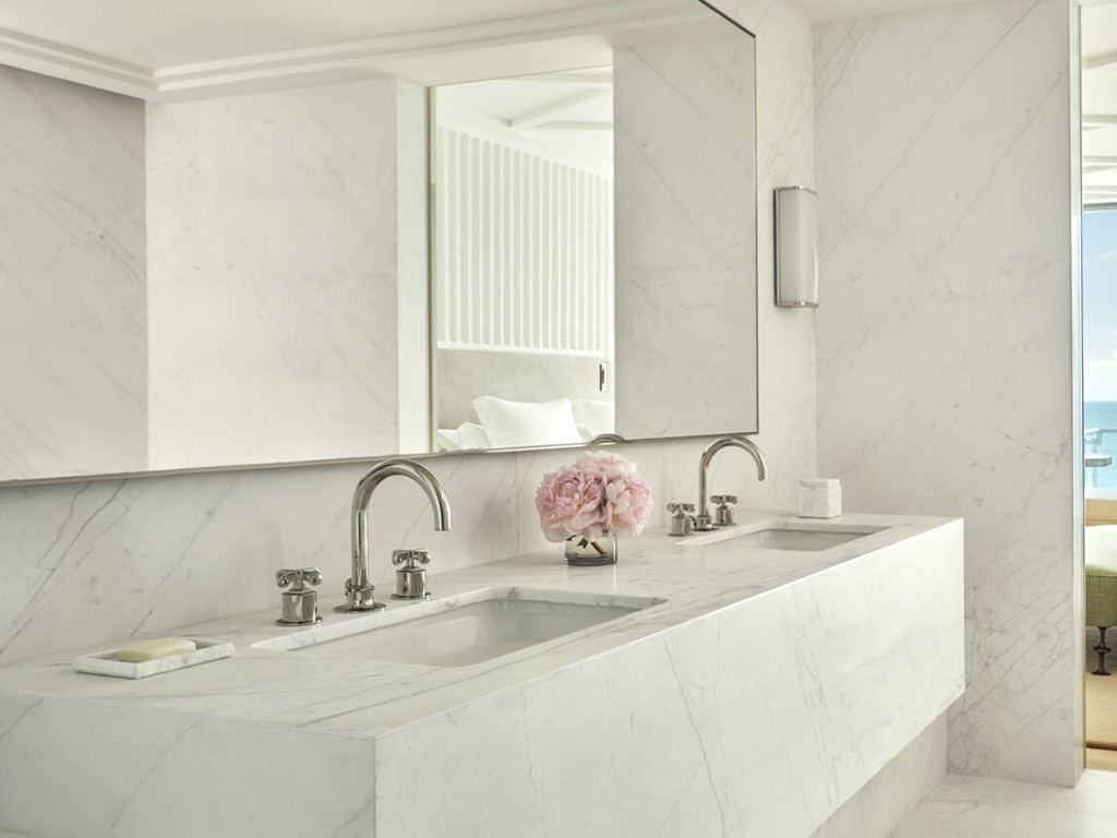 Close up of a luxury classic hotel bathroom with white marble on bath wall, floor, sink and bath counter
