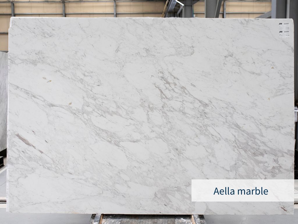 Slab of the white Greek marble Aella with brown and gray veins on its surface and placed in an indoor warehouse of a natural stone supplier