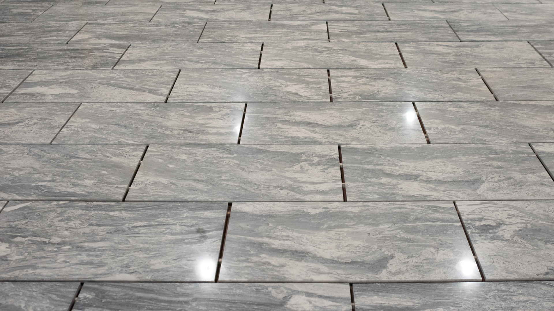 Close-up image of grey marble tiles with a cloudy surface placed perfectly with the dry lay method