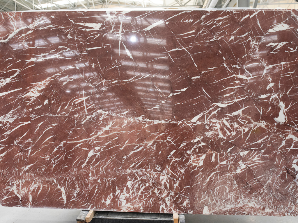 Ribeye red colored marble slab with intricate white veins in interior warehouse by Stone Group International. Some Of The Best-colored Marbles That You Need To Know