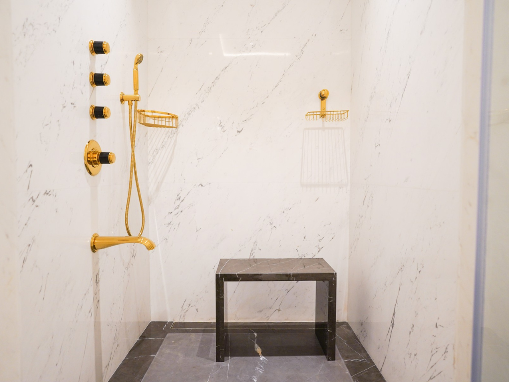 Rendering of a luxurious bathroom with white marble vein matching for a striking effect, with gold and wooden elements